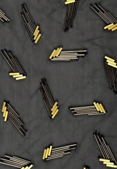 many pins are placed together on a black surface with some yellow ones in the middle