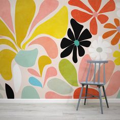 a chair sitting in front of a wall with flowers painted on it's side