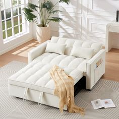 a white couch sitting on top of a rug in a living room next to a window