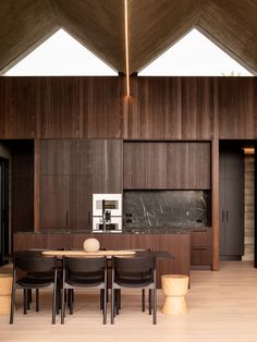 a dining table and chairs in a room with wood paneling on the walls above it