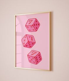 three pink dices on a pink background in a gold frame hanging on the wall