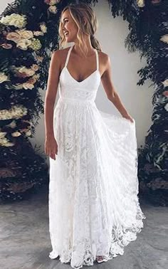 a woman wearing a white dress standing in front of flowers