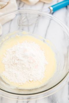 a glass bowl filled with batter and flour