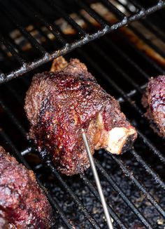 steaks being cooked on the grill with tongs