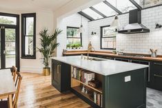 a kitchen with wooden floors and black cabinets, an island countertop and two windows