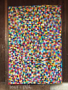 a multicolored quilt hanging on the side of a wooden wall