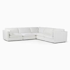 a white sectional couch with pillows on the top and bottom corner, facing away from the camera