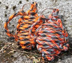 two orange and black rope bags sitting on the ground next to each other in front of a rock