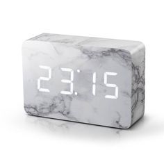 an alarm clock with the time displayed on it's marble surface, which is white