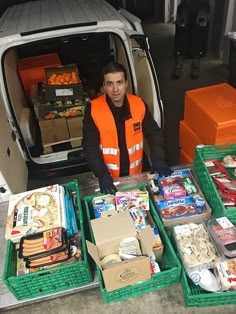 a man in an orange vest standing next to boxes of food