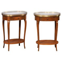 two wooden side tables with glass tops on each end and gold trimming around the edges