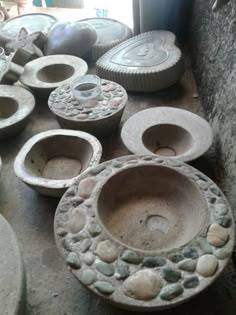 several bowls and plates are sitting on the floor next to each other in an area that is covered with stone