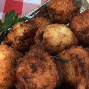 some fried food is sitting on a plate with parsley in the foreground and red checkered table cloth behind it