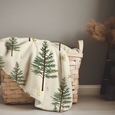 a basket with a blanket sitting on top of it next to a potted plant