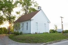 an old white church sitting on the side of a road