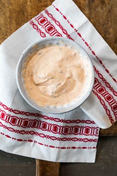 a bowl of dip sitting on top of a white napkin next to a wooden spoon