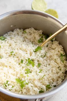 rice and cilantro in a silver pot with a wooden spoon next to it