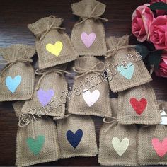 small burlock bags filled with hearts on top of a wooden table next to pink roses