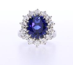 a blue and white diamond ring on a white surface with the center stone surrounded by smaller diamonds