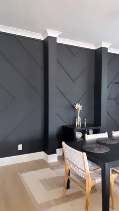 a dining room with black painted walls and white trim on the wall, along with wooden chairs