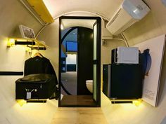 an airplane bathroom with black and white appliances on the wall, and yellow accents around the toilet