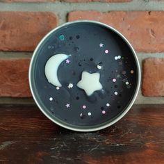 a black plate with white stars and a moon on it sitting on a wooden table