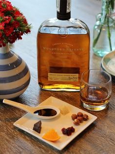 a bottle of woodford reserve on a table next to a bowl of fruit and nuts