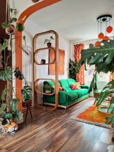 a living room filled with green furniture and lots of plants on top of wooden floors