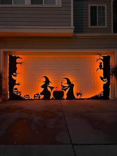 a garage door decorated with halloween silhouettes and pumpkins in front of a house