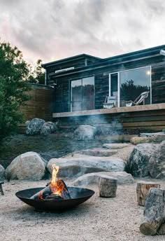 a fire pit sitting in front of a house on top of a gravel covered field