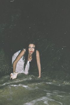 a woman is kneeling down in the water