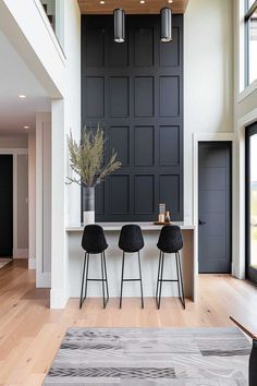 three stools sit in front of a counter with two vases on it and an open floor plan