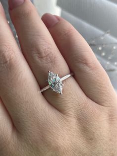 a woman's hand with a diamond ring on top of her finger and the other hand holding an engagement ring