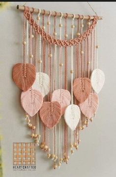 a pink and white wall hanging with shells on it's sides, along with pearls