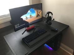 a desk with a keyboard, mouse and headphones on it next to a computer monitor