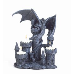 a statue of a dragon sitting on top of a castle with candles in front of it