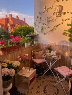 an outdoor patio with potted plants and flowers on the table, next to two chairs