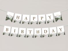 a happy birthday banner with mountains and trees in the background, hanging on a string