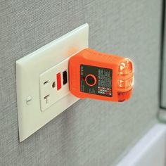 an orange light switch sitting on top of a wall