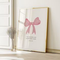 a pink bow sits on the floor next to a framed photograph