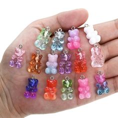 small teddy bear charms in various colors are held by a person's left hand