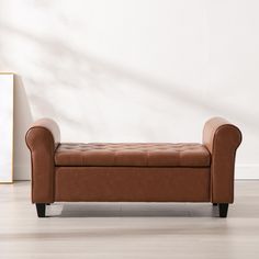 a brown leather bench sitting in front of a white wall