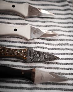 three knives sitting on top of a striped cloth