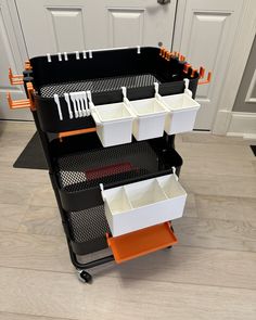 three black and white containers on wheels with orange handles