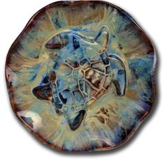 a blue and brown plate with a turtle on it's face in the center