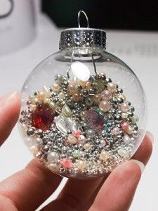 a hand holding a glass ornament filled with beads