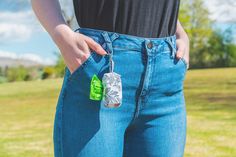 a person wearing blue jeans and holding a green bottle in their pocket with the tag on it