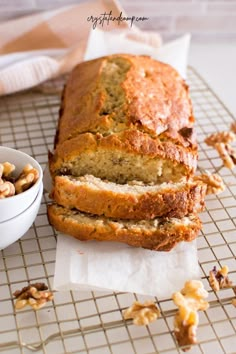 a loaf of bread sitting on top of a cooling rack next to a bowl of nuts