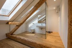 an attic bathroom with wooden floors and skylights above the toilet area is shown in this image