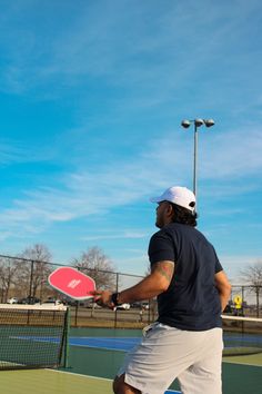 a man holding a tennis racquet on top of a tennis court with blue sky in the background